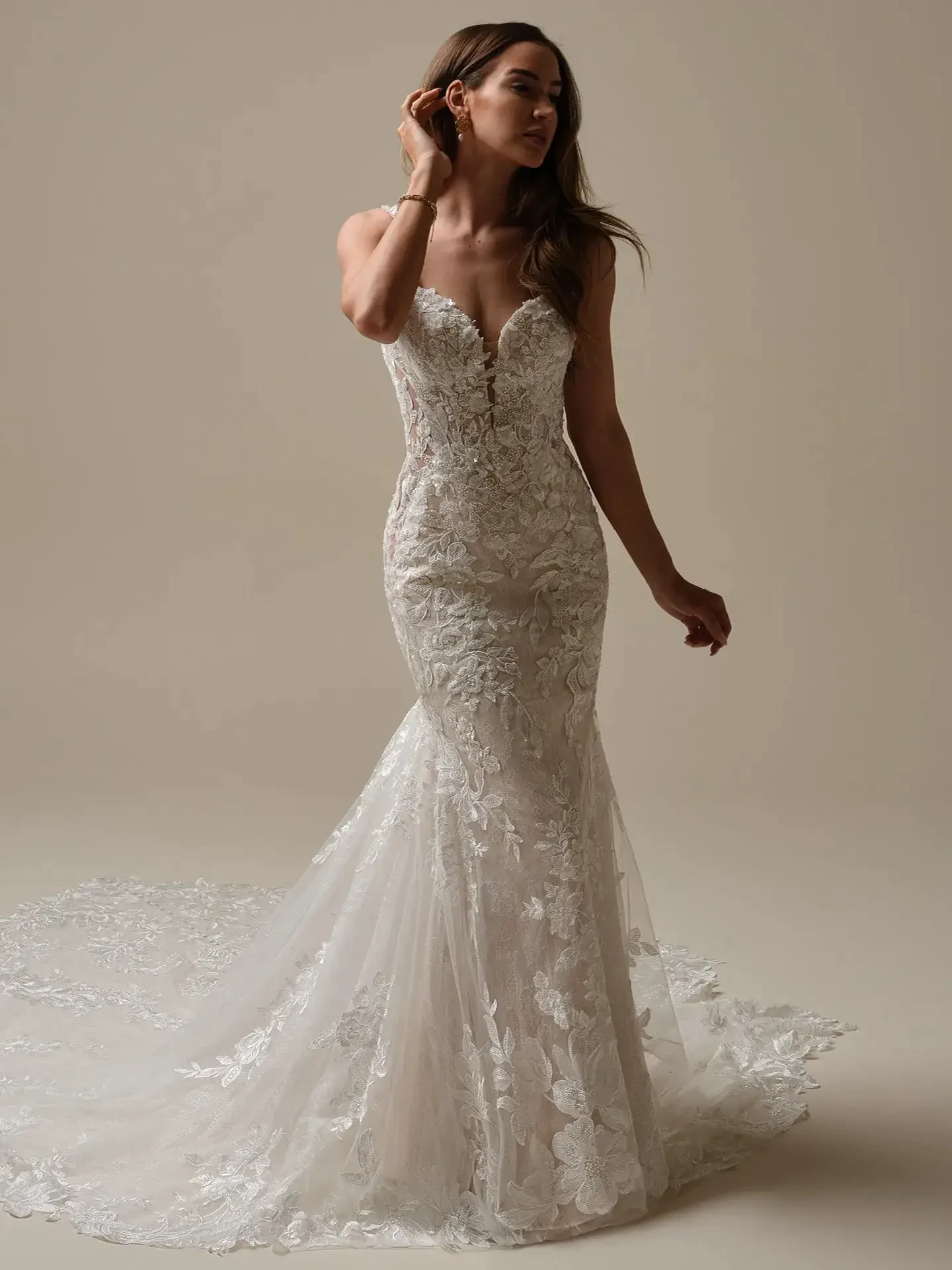 Model is wearing a sleeveless beaded lace fit and flare wedding dress