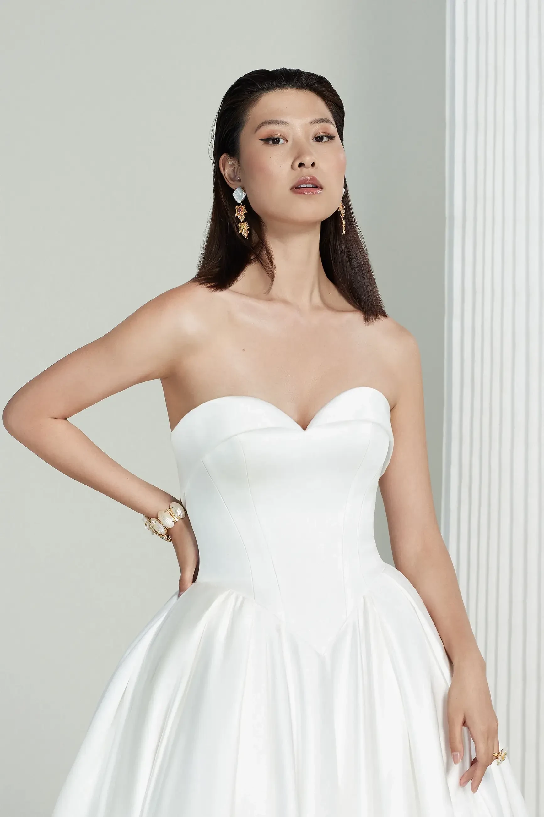 Model is wearing a strapless ball gown wedding dress with a basque waist