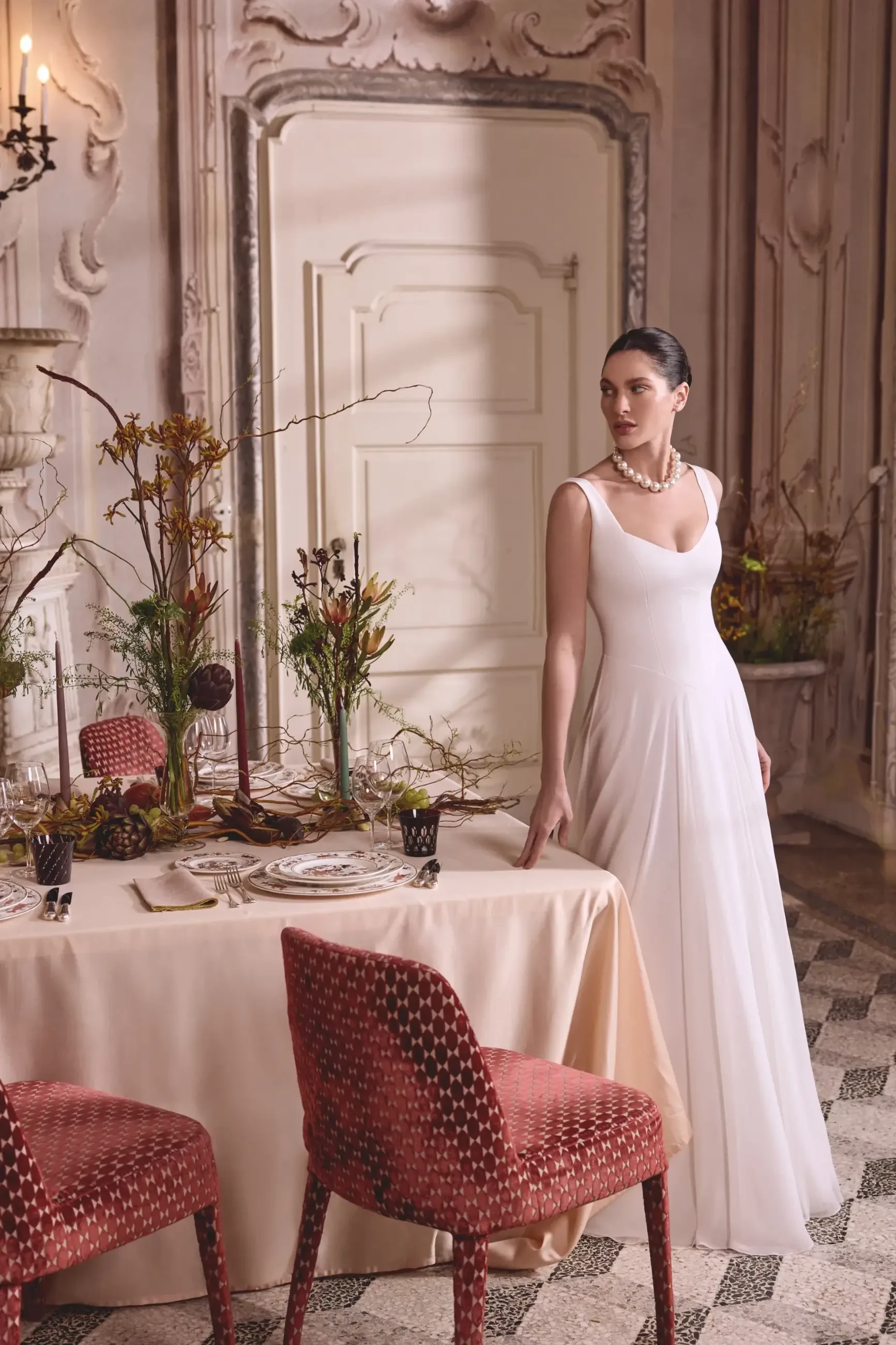 model is wearing a sleeveless sheath wedding gown