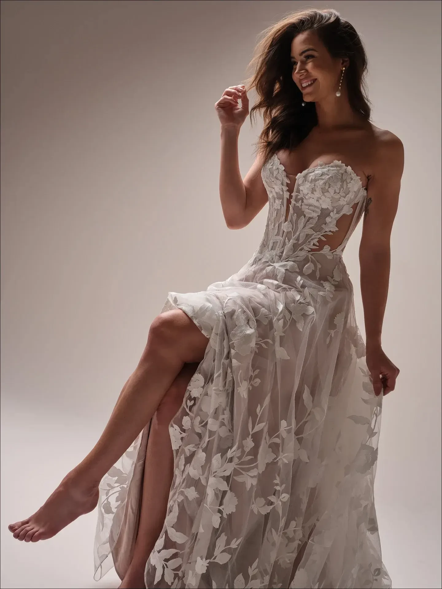 Model is wearing an A-line bridal dress with floral appliqués, illusion panels, and a flattering, modern silhouette.
